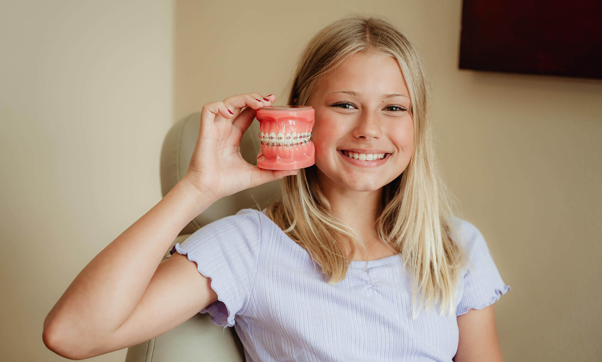 young girl holding teeth model with braces