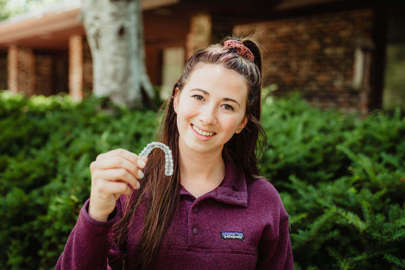 woman holding aligners smiling